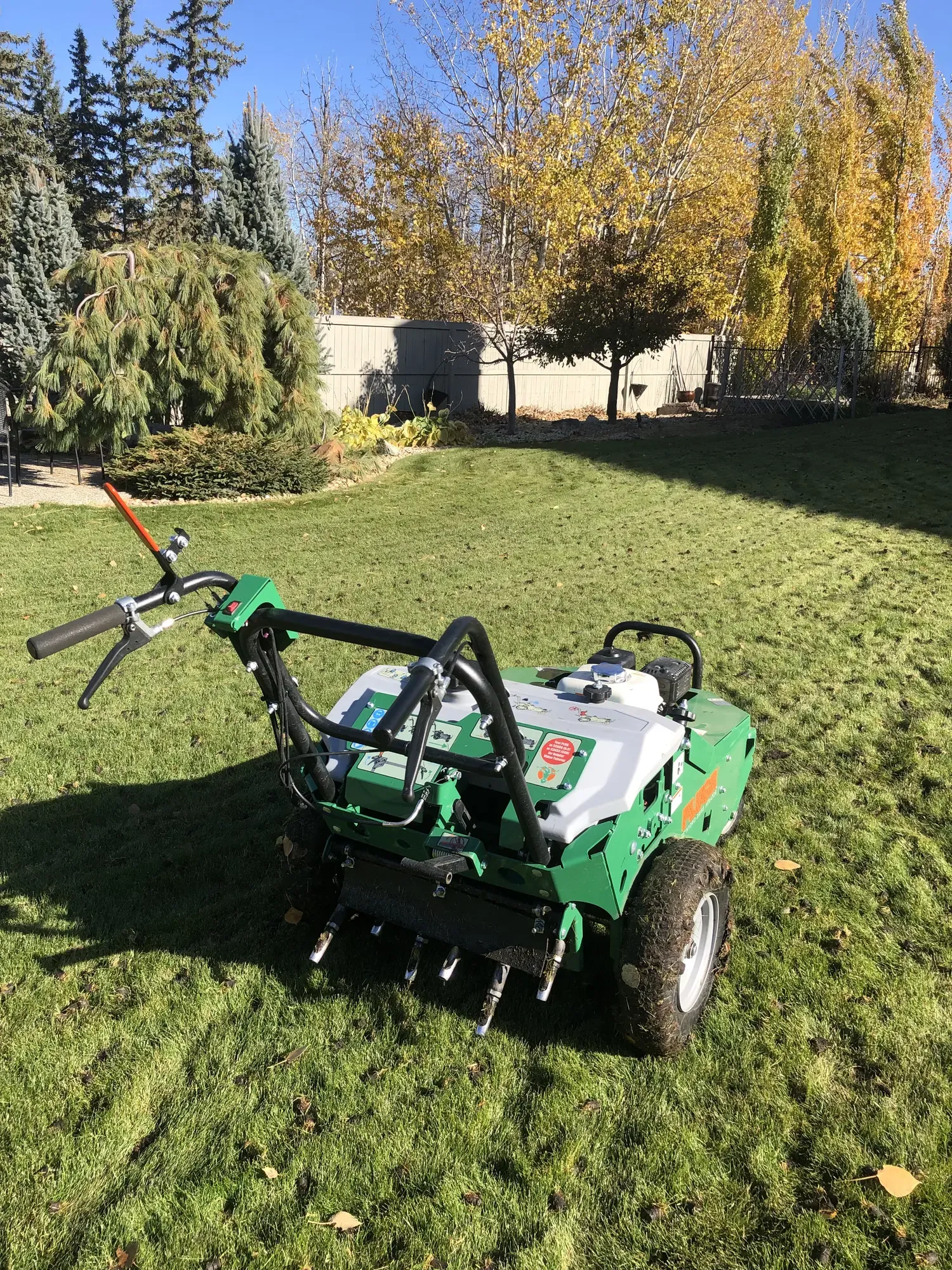 Close-up of aerator machine on autumn lawn showing soil plugs