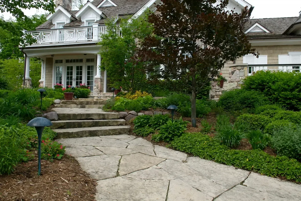 Professionally landscaped shrubs and trees along stone walkway