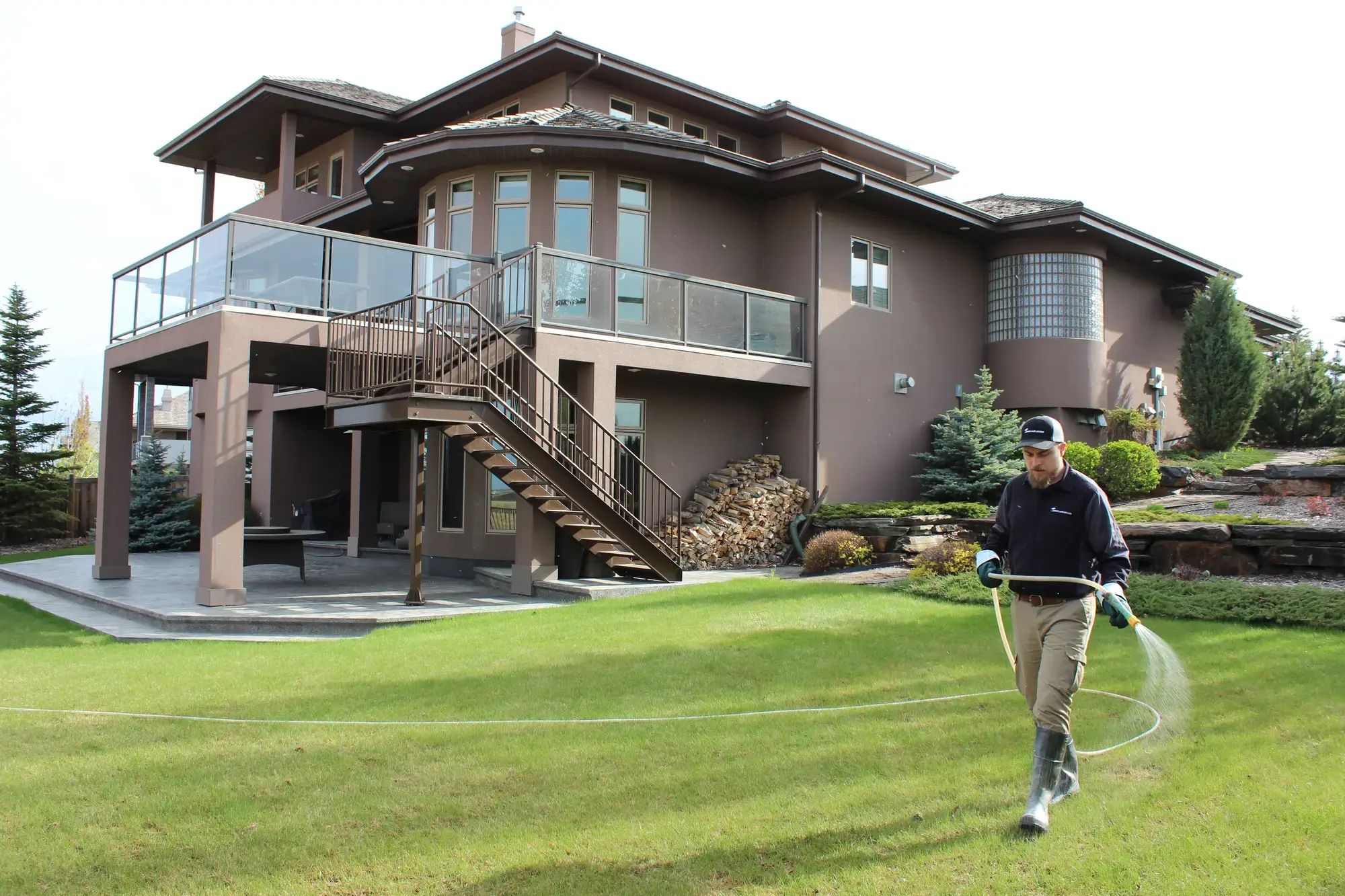 Green Oasis Services technician spraying a luxury home backyard