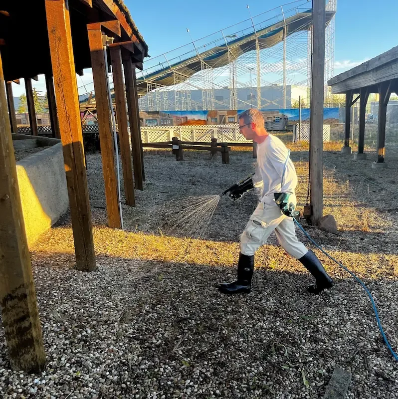 Technician spraying vegetation control on gravel yard