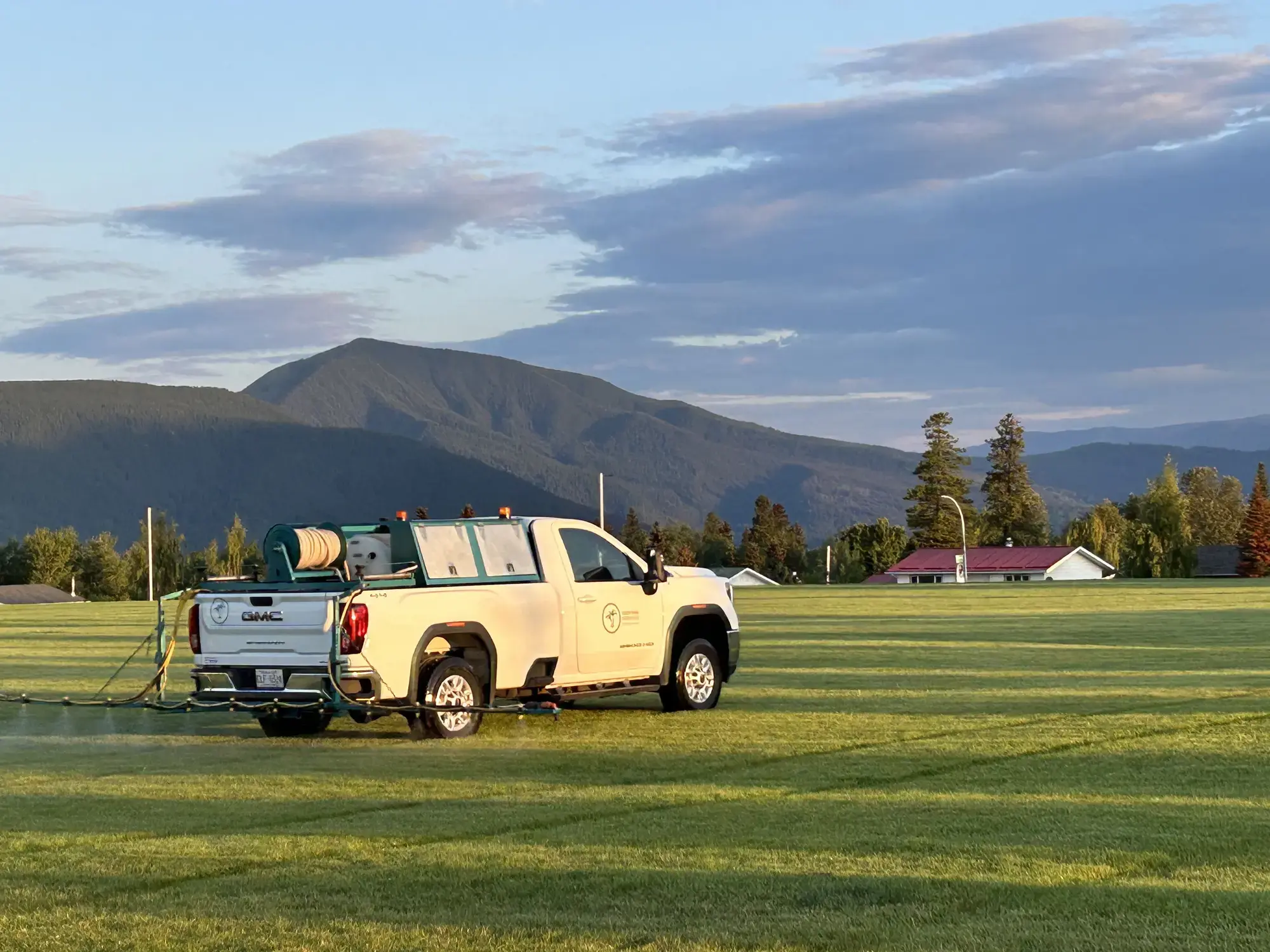 Green Oasis truck spraying field with mountain backdrop
