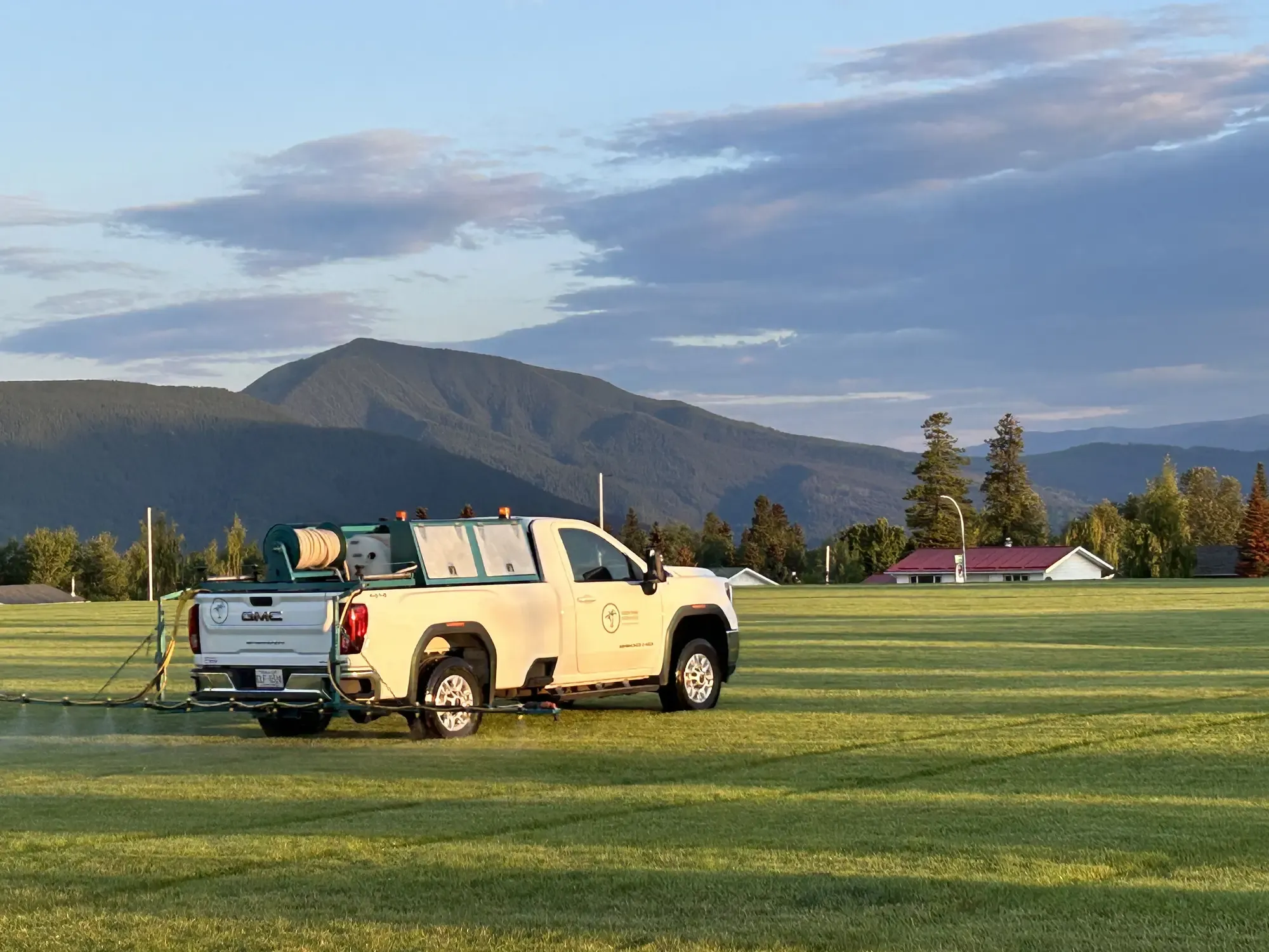 Green Oasis truck spraying field with mountain backdrop